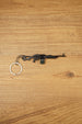 PKM rifle keyring laid flat on a wooden surface, showing the full metal LMG design with chain and key ring for FPS gamer gift use