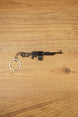 PKM rifle keyring laid flat on a wooden surface, showing the full metal LMG design with chain and key ring for FPS gamer gift use