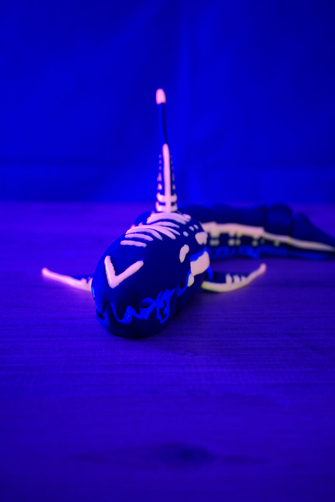 Close front angle of Marrowbreach inspired alien sea creature figure glowing under UV light with pink facial details and poseable mouth area.