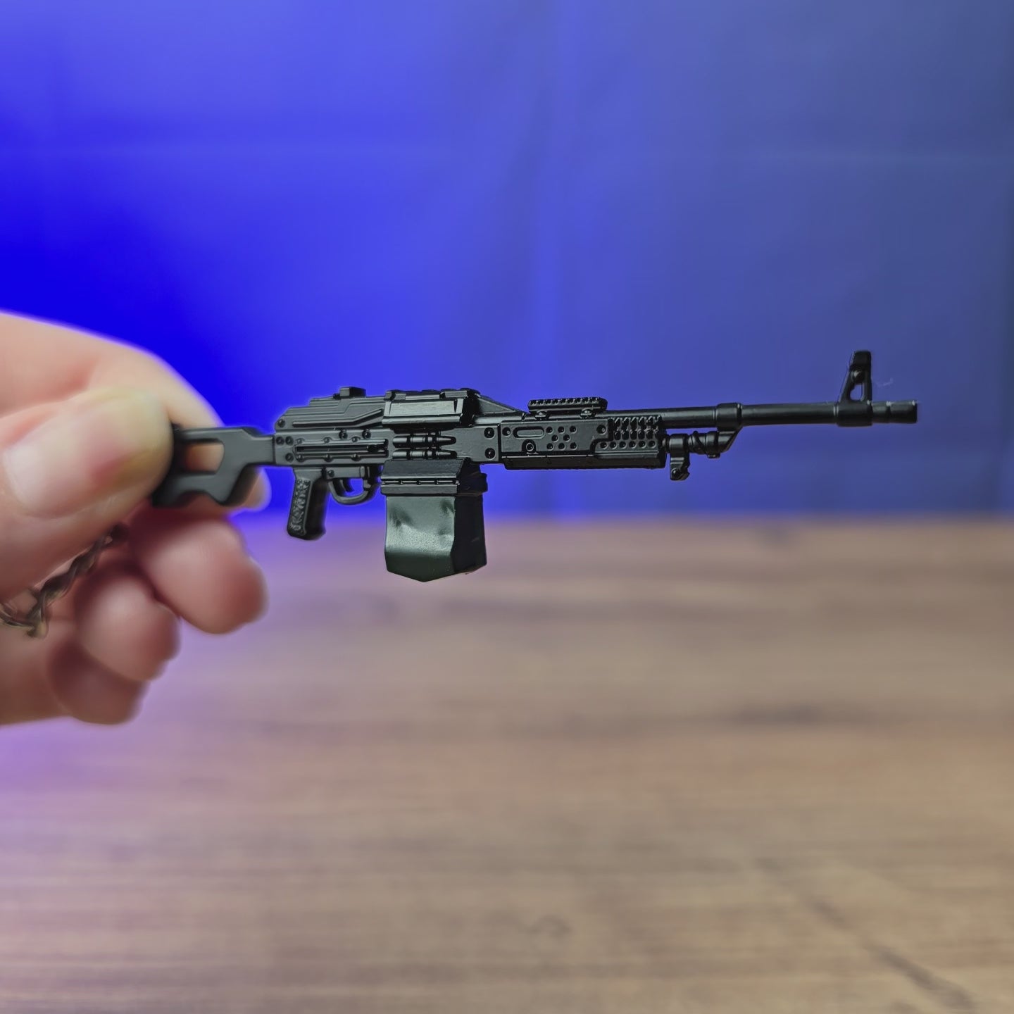 PKM rifle keyring shown being held and rotated by hand, designed as a miniature LMG-inspired gamer accessory or keychain.