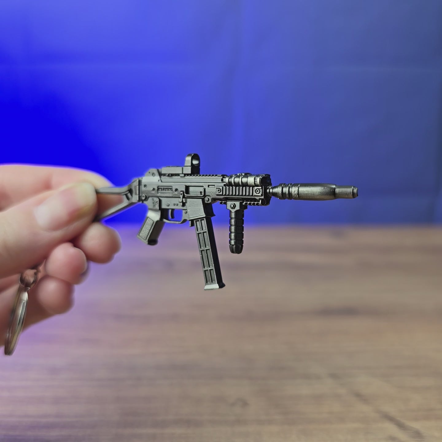 UMP45 submachine gun keyring shown being held and rotated by hand, designed as a miniature SMG-inspired gamer accessory or keychain.