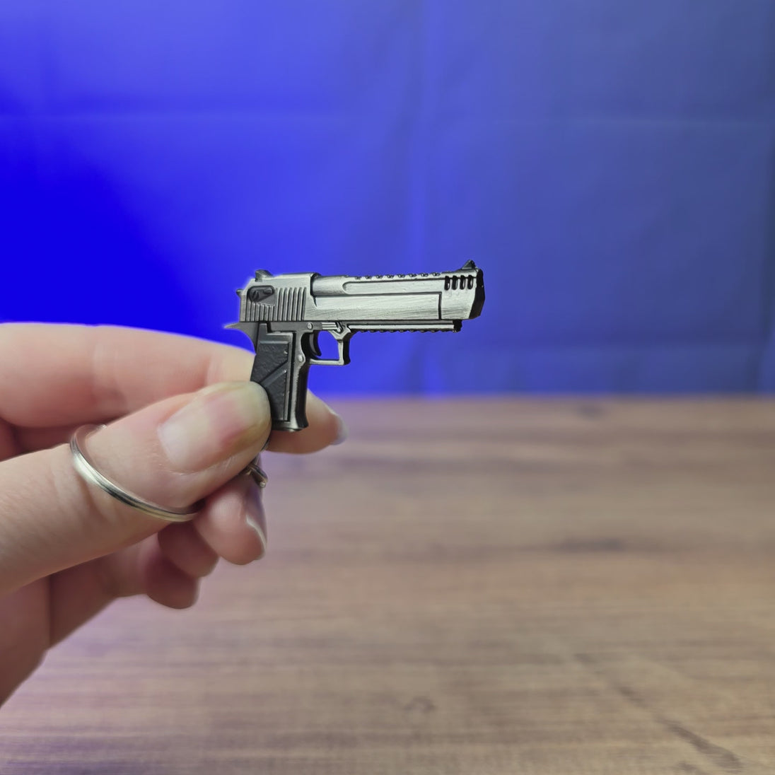 Desert Eagle pistol keychain replica shown being held and rotated by hand, designed as a miniature pistol-inspired accessory or keyring.
