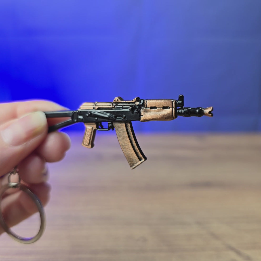 3D-printed AKS-74U rifle keyring shown being held and rotated by hand, designed as a miniature FPS-inspired accessory or gamer gift.