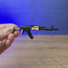 AK-74 rifle keyring shown being held and rotated by hand, designed as a miniature rifle-inspired gamer accessory or keychain.