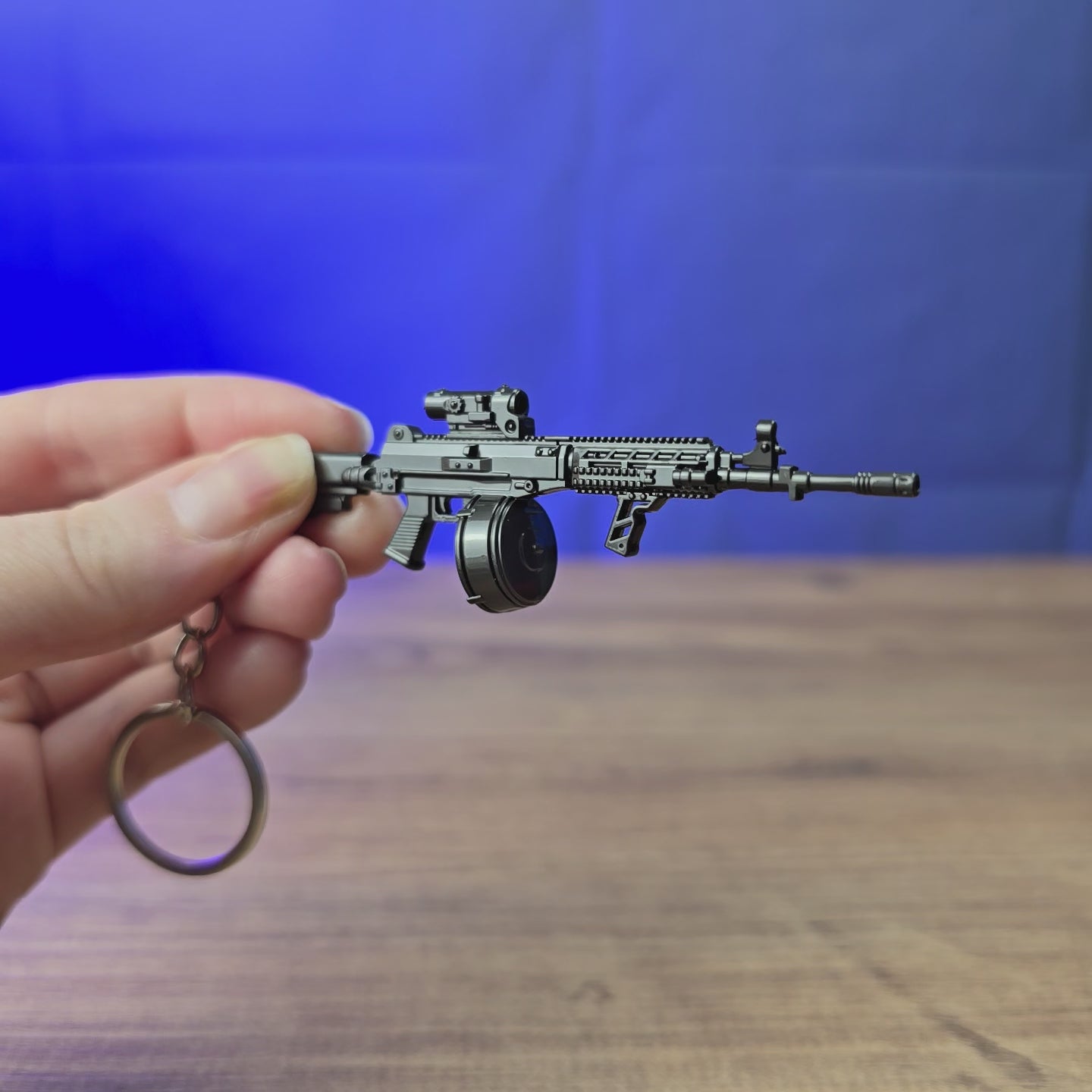 3D-printed AK12 rifle keyring with drum magazine shown being held and rotated by hand, designed as a miniature rifle-inspired accessory or keychain.