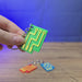 3D-printed Factorio circuit keyring shown being held and rotated by hand, with a compact circuit-inspired design and keychain loop.