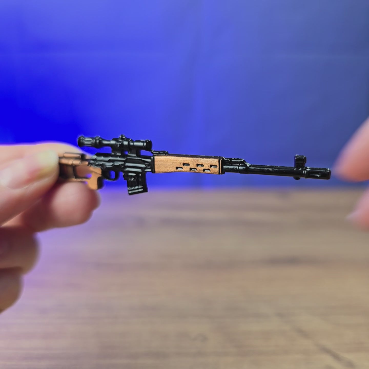 SVDS rifle metal keyring shown being held and rotated by hand, designed as a miniature rifle-inspired gamer accessory or keychain.