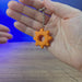 3D-printed Factorio cog keyring with a gear-shaped design and keychain loop, shown being held and rotated by hand.