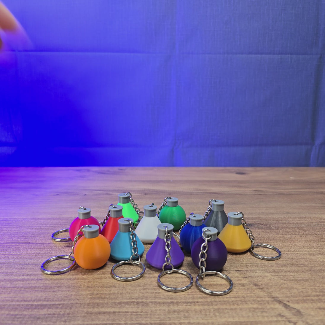 3D-printed Factorio flask keyring shown being held and rotated by hand, with a compact flask-shaped design and keychain loop.