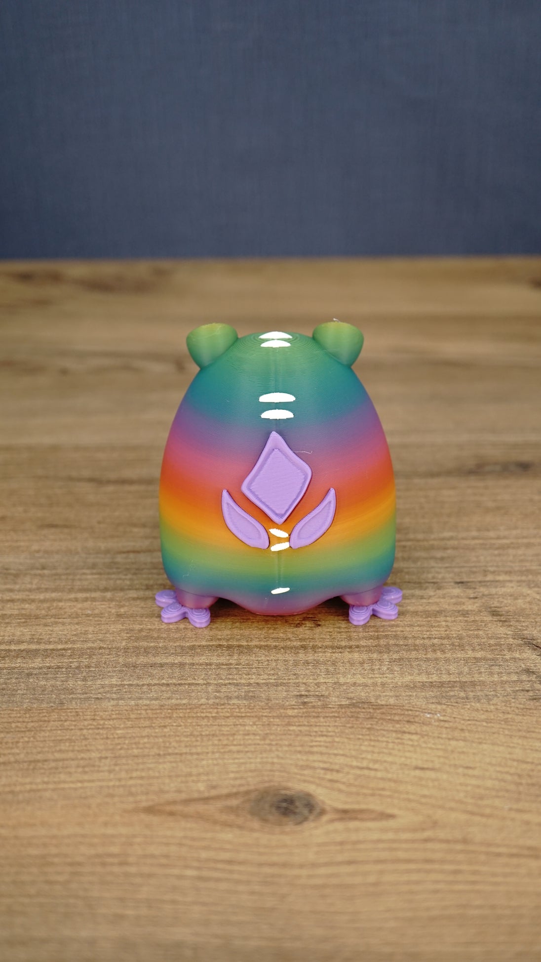 Back view of a rainbow Frogbert plush figure showing purple back details, white markings, and colorful gradient body.