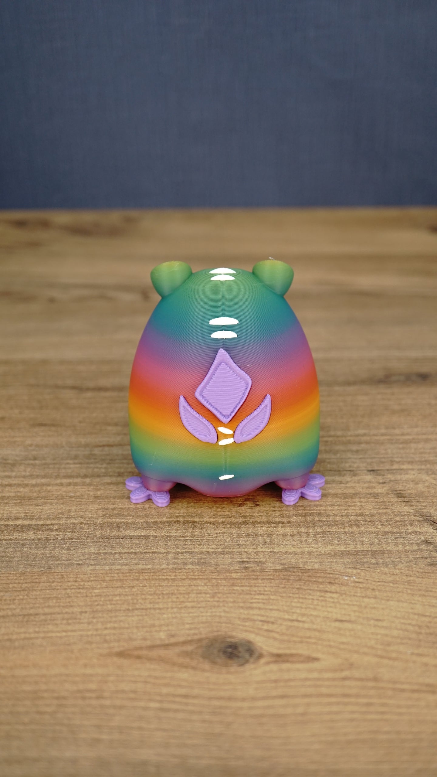 Back view of a rainbow Frogbert plush figure showing purple back details, white markings, and colorful gradient body.