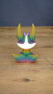 Back view of a rainbow Kitsuu figure showing its large ears, white head marking, and gradient tail colors.
