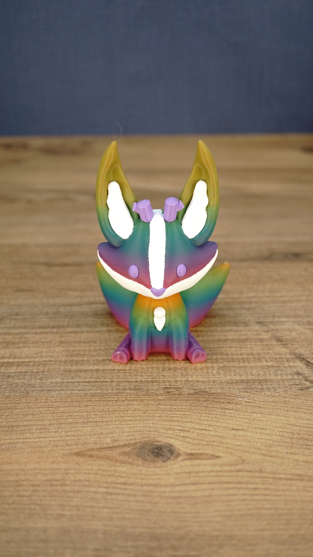 Front view of a rainbow Kitsuu figure with tall ears, white face markings, purple details, and a colorful gradient body.