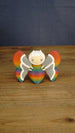 Front view of the Rainbow-Tipped Butterfly Plush figure with a rainbow body, grey and white wings, beige face and curved white antennae