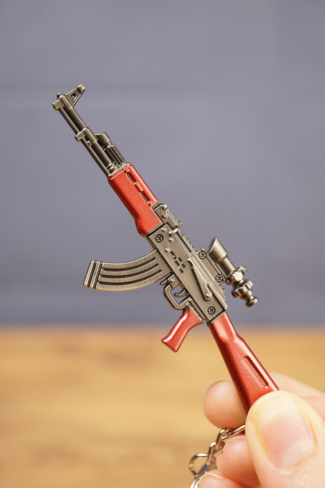 Red modded AKM rifle keychain close-up with optic, curved magazine and metallic finish, ideal gamer gift for FPS collectors