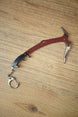 Full Red Rebel ice pick keyring replica displayed on a wooden tabletop, showing the curved red handle, black grip, silver pick, and attached keyring.