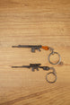 SA58 FAL battle rifle keychains in base and modded styles on a wooden surface, showing metal keyrings and detailed gunmetal finishes
