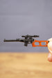 Close-up of scoped VSS Vintorez style keychain held between fingers, showing orange stock detail and miniature rifle shape