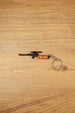 Scoped VSS Vintorez style rifle keychain with orange stock detail and silver keyring shown on a wooden surface