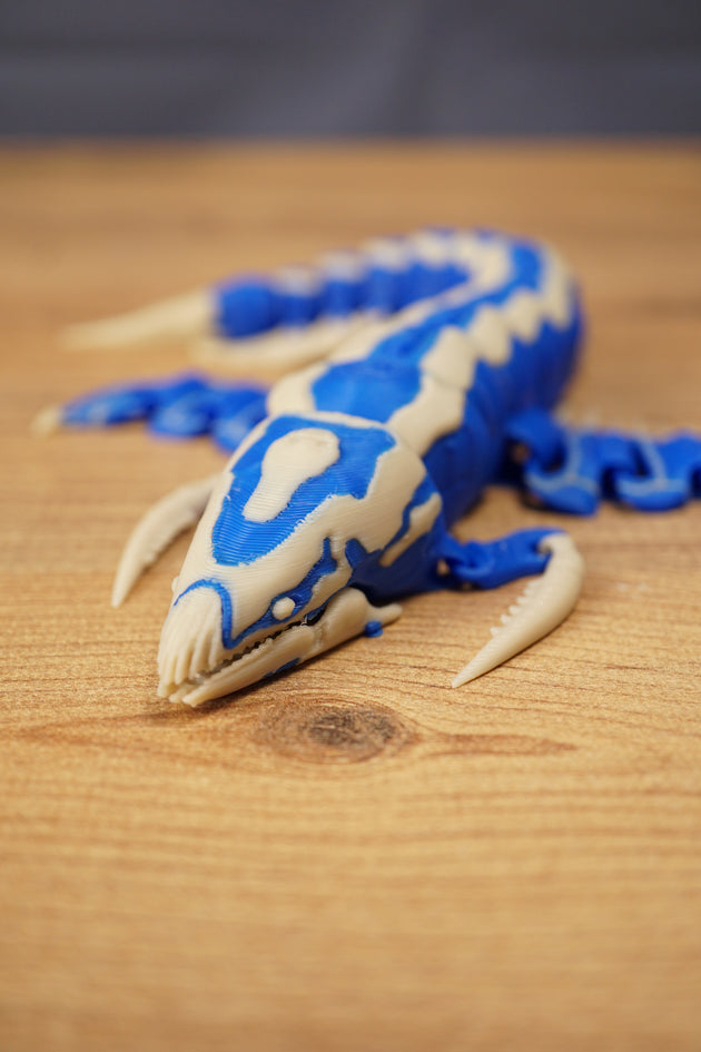 Front angled view of the Shiver Leviathan figure with open jaw, curved claw, blue body, and bone colour markings.