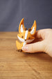 Small Ancient Kitsuu fox figure held between fingers with orange body, white chest detail, brown paws and oversized ears