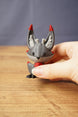 Small Obsidian Kitsuu figure held in hand with grey body, red-tipped ears, white ear details and curled tail on display
