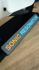 Close-up of Sonic Resonator display stand nameplate with raised orange and cyan lettering beneath the Subnautica 2 inspired collectible replica