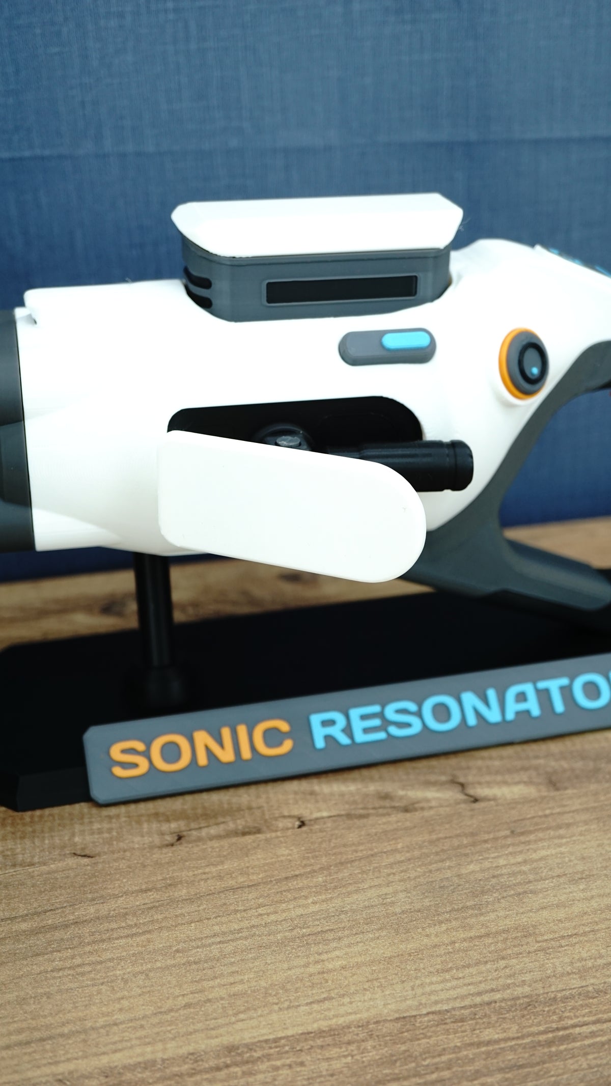 Close side view of Subnautica 2 Sonic Resonator replica showing the white body panels, side control, cyan detail and Sonic Resonator display stand