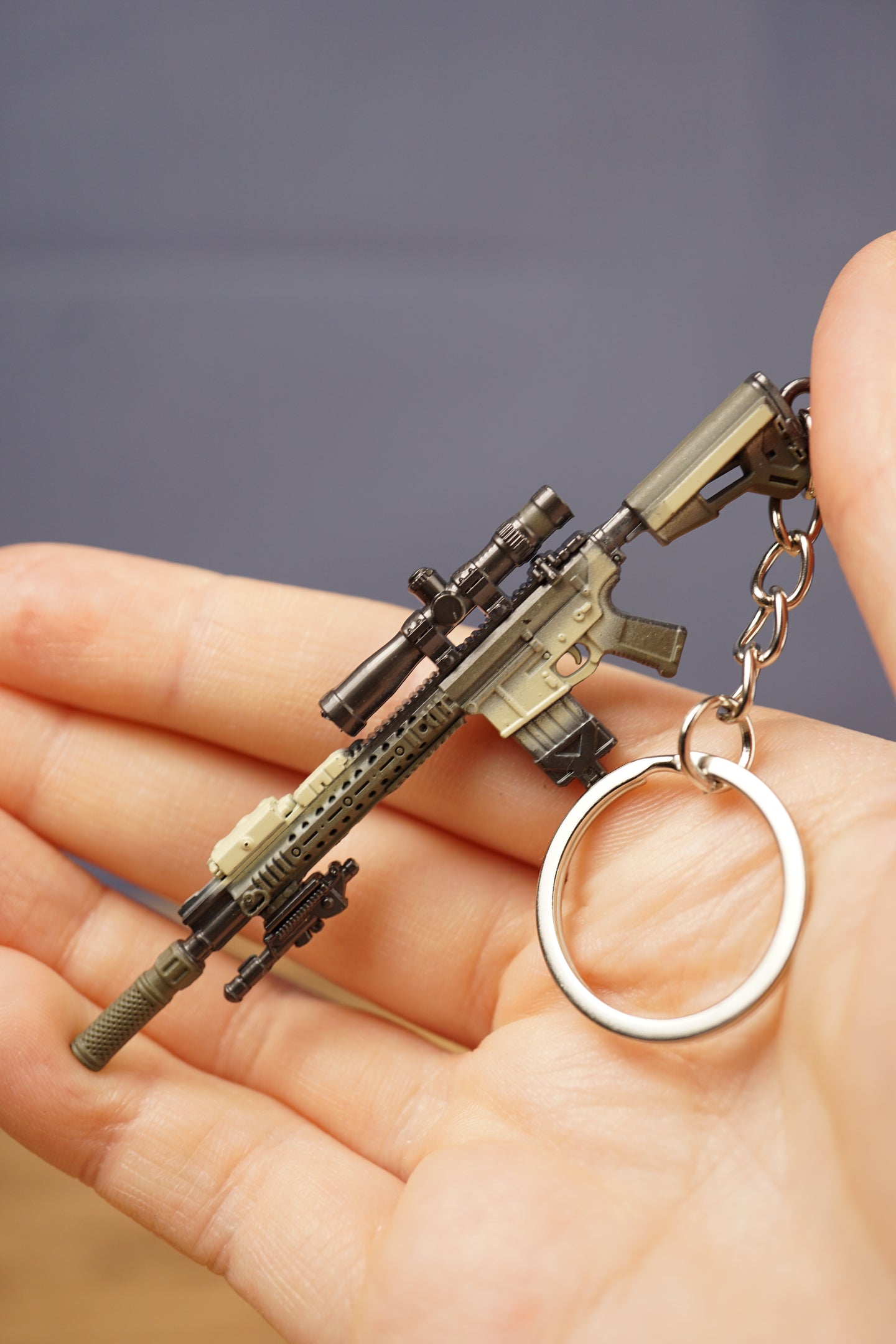 Detailed SR-25 tactical rifle keychain resting in hand with visible scope, magazine, stock, barrel, chain, and circular keyring attachment.