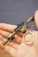 Detailed SR-25 tactical rifle keychain resting in hand with visible scope, magazine, stock, barrel, chain, and circular keyring attachment.