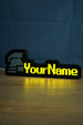 Illuminated standard ironman nameplate glowing in the dark with a grey helmet icon, yellow lettering, and soft reflection on the tabletop.