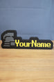 RuneScape-style standard ironman nameplate with a grey helmet icon, yellow custom lettering, and black frame displayed on a wooden desk.