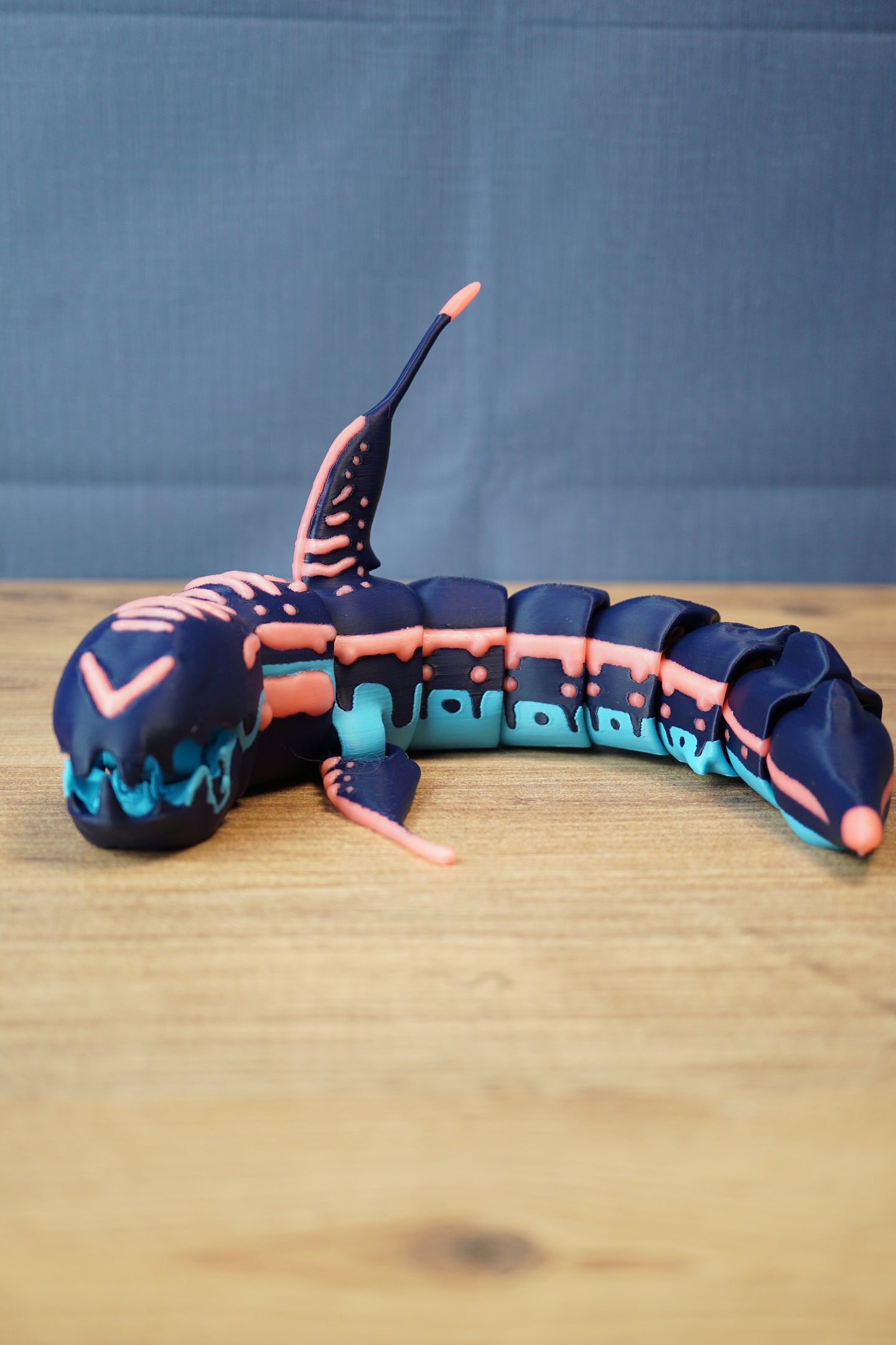 Full side view of articulated Marrowbreach inspired figure with segmented body, tall dorsal fin, dark blue shell and bright light blue underside.