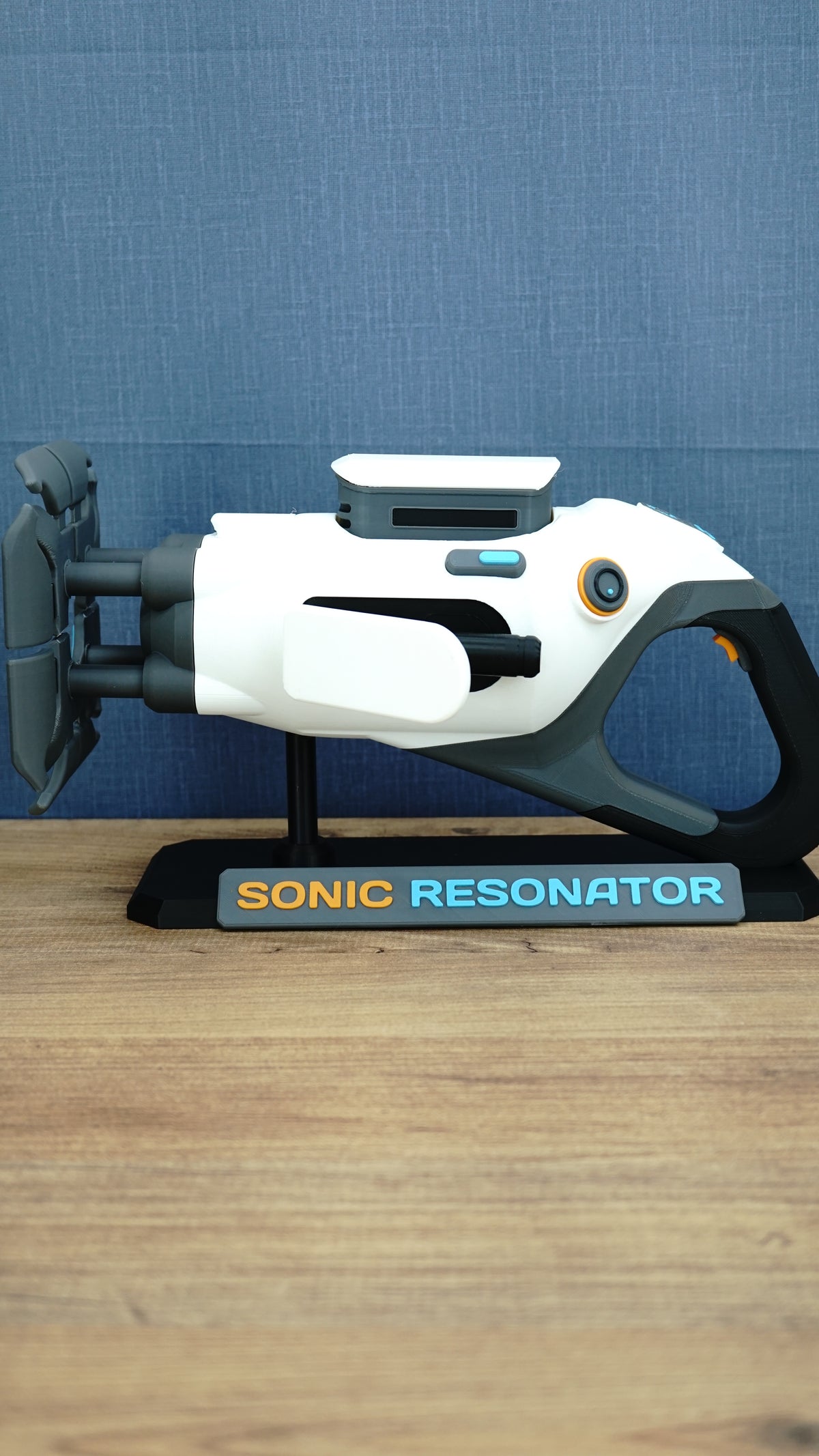 Subnautica 2 Sonic Resonator replica displayed side-on with white and grey body, cyan and orange details, and included collector display stand