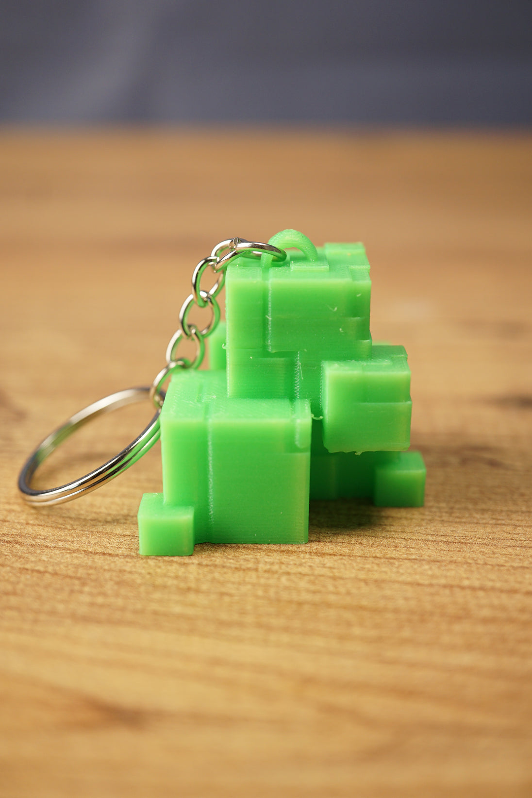 Mini Subnautica ion cube keychain in bright green with blocky cube details, metal chain, and keyring displayed on a wooden surface.