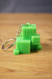 Mini Subnautica ion cube keychain in bright green with blocky cube details, metal chain, and keyring displayed on a wooden surface.