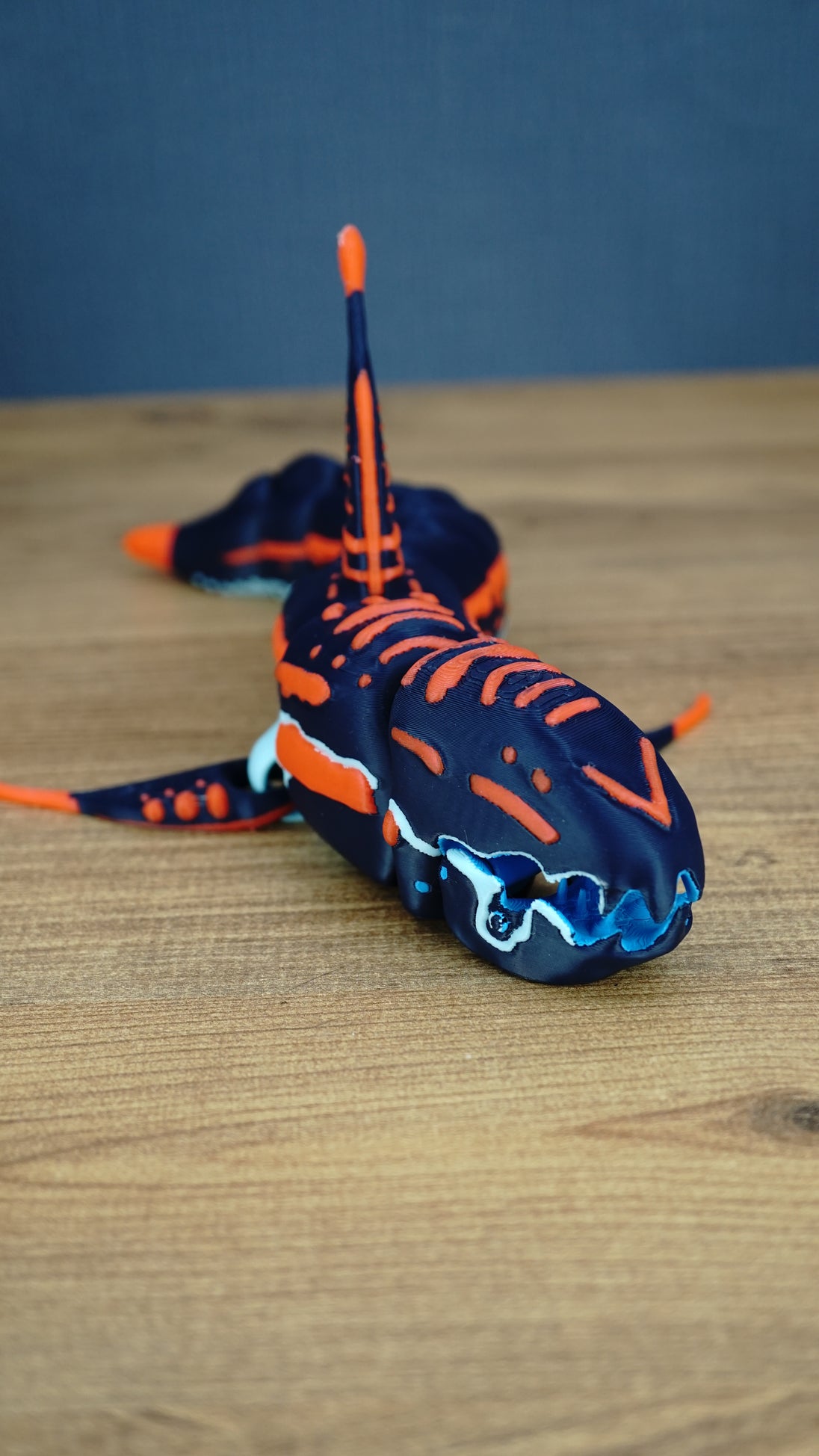 Close front view of an articulated Subnautica Marrowbreach figure showing its dark blue head, orange markings, blue mouth parts, side fins, and tall dorsal fin.