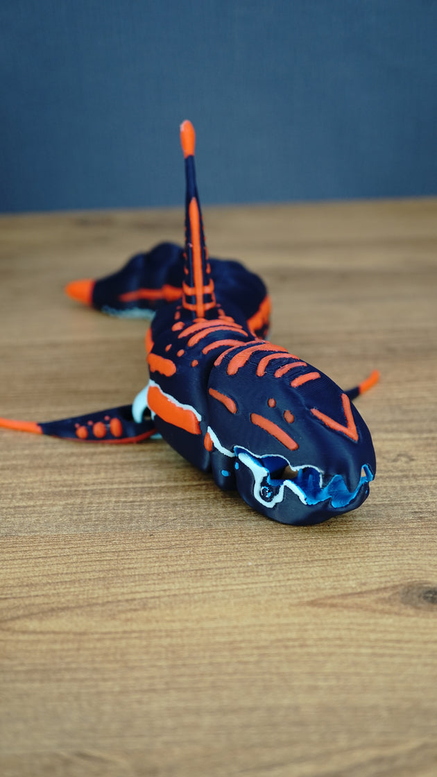 Close front view of an articulated Subnautica Marrowbreach figure showing its dark blue head, orange markings, blue mouth parts, side fins, and tall dorsal fin.