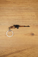 SVDS rifle metal keyring laid flat on a wooden surface, showing the long barrel, scope, bronze stock and split keyring attachment