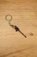 SVDS-style sniper rifle metal keyring displayed diagonally on a wooden table, ideal as a gamer gift or collectible accessory