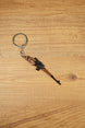 SVDS-style sniper rifle metal keyring displayed diagonally on a wooden table, ideal as a gamer gift or collectible accessory