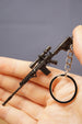 Modded tactical rifle keychain in hand with scope-style accessory, dark metal finish, magazine detail and circular keyring