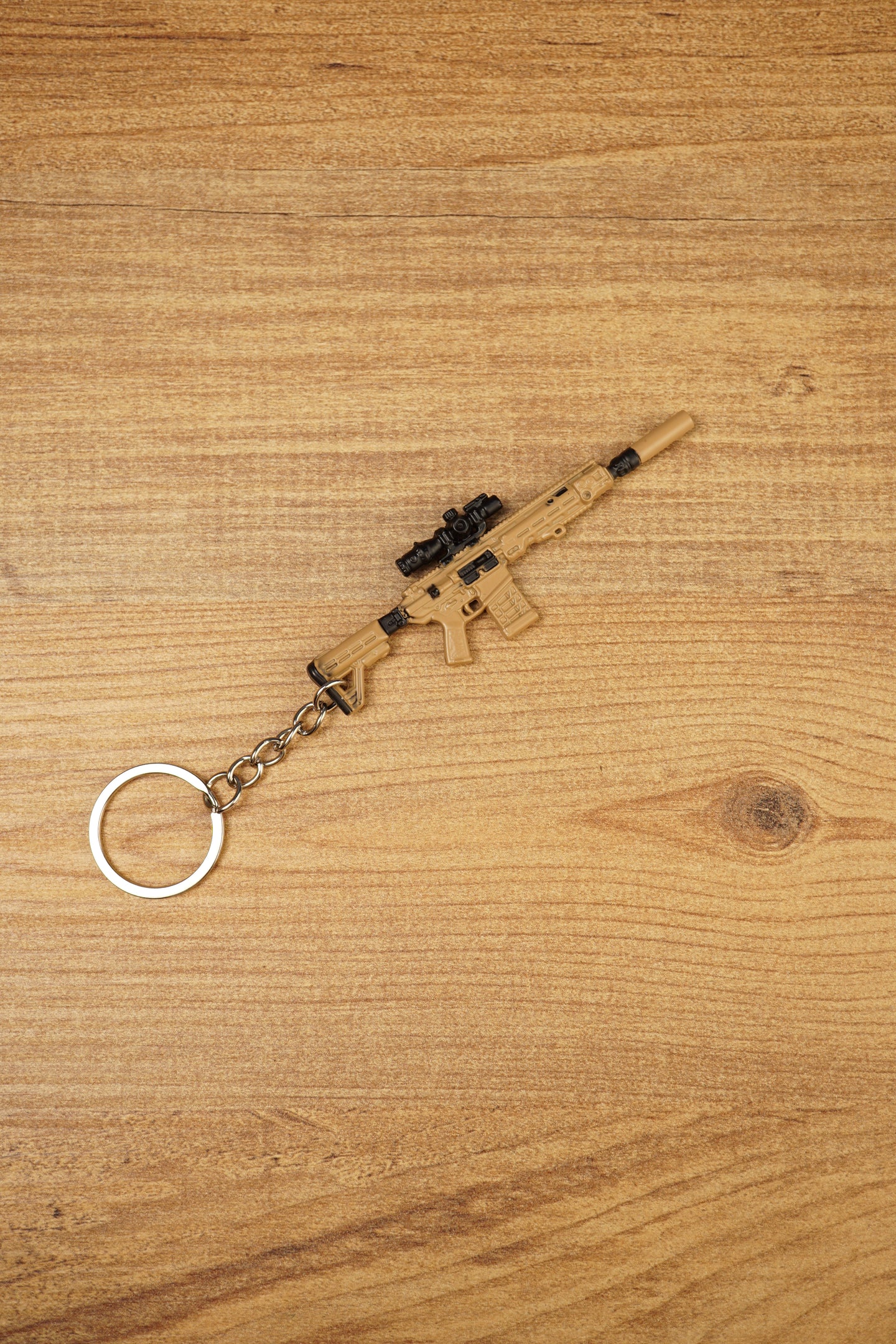 Angled tan MCX-SPEAR inspired rifle keyring with black optic detail and metal chain on wood, ideal gaming collectible gift