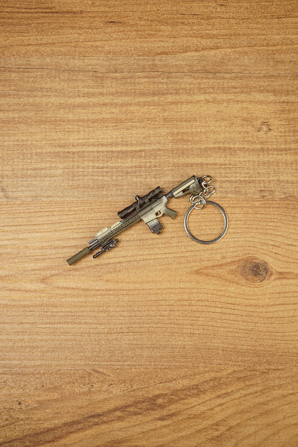 Angled SR-25 rifle keychain on wood with detailed scope, barrel, stock, magazine, and circular keyring for tactical shooter fans and collectors.