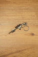 Angled SR-25 rifle keychain on wood with detailed scope, barrel, stock, magazine, and circular keyring for tactical shooter fans and collectors.