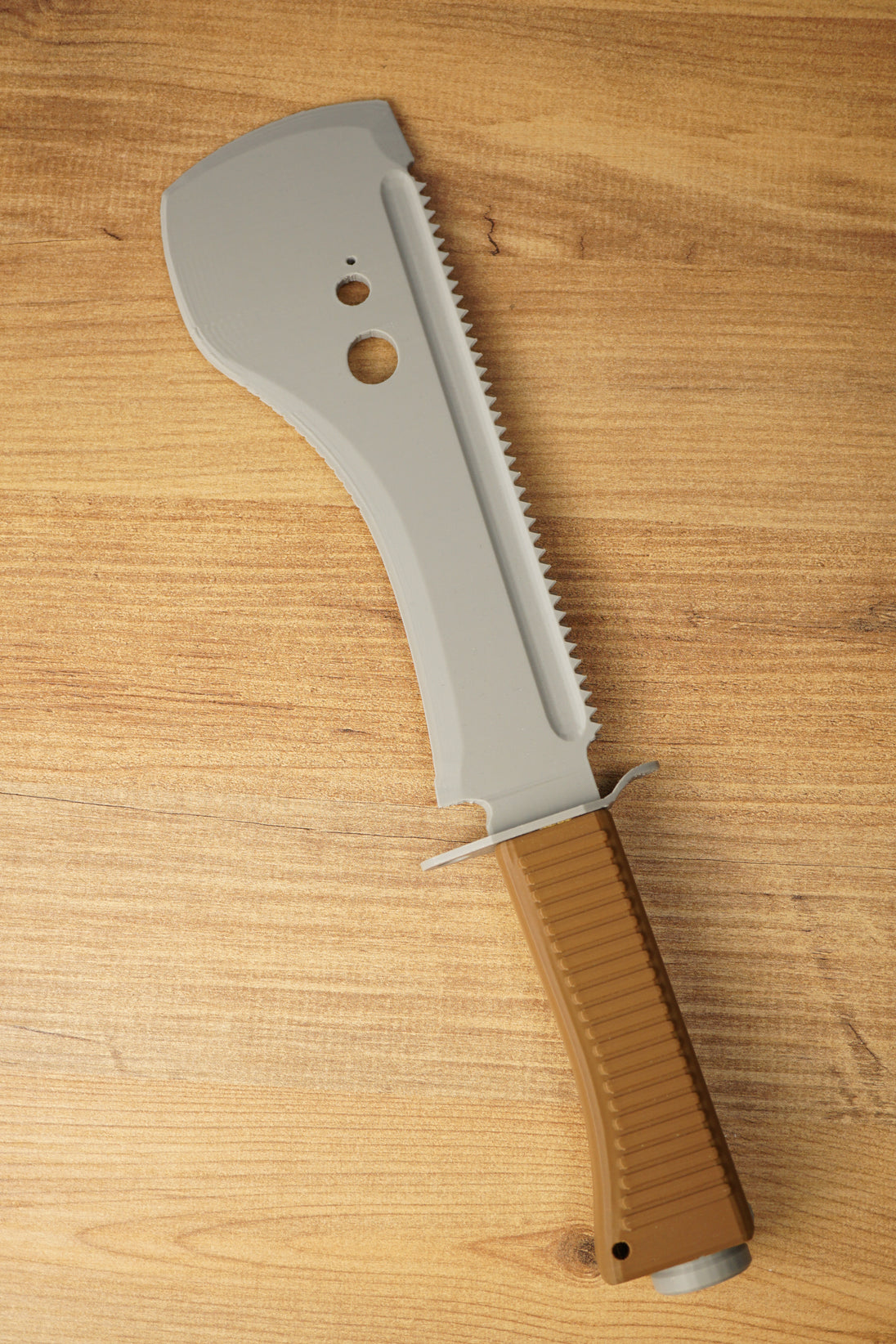 Top-down view of a 3D-printed UVSR Taiga-1 survival machete replica on a wooden tabletop.