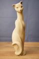Single tall beige cat figurine replica standing upright on a wooden surface, featuring a long neck, curved tail, and minimalist sculpted face.