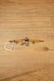 Tan and black tactical rifle keyring with detailed grip, sight and front attachment on a wooden background.