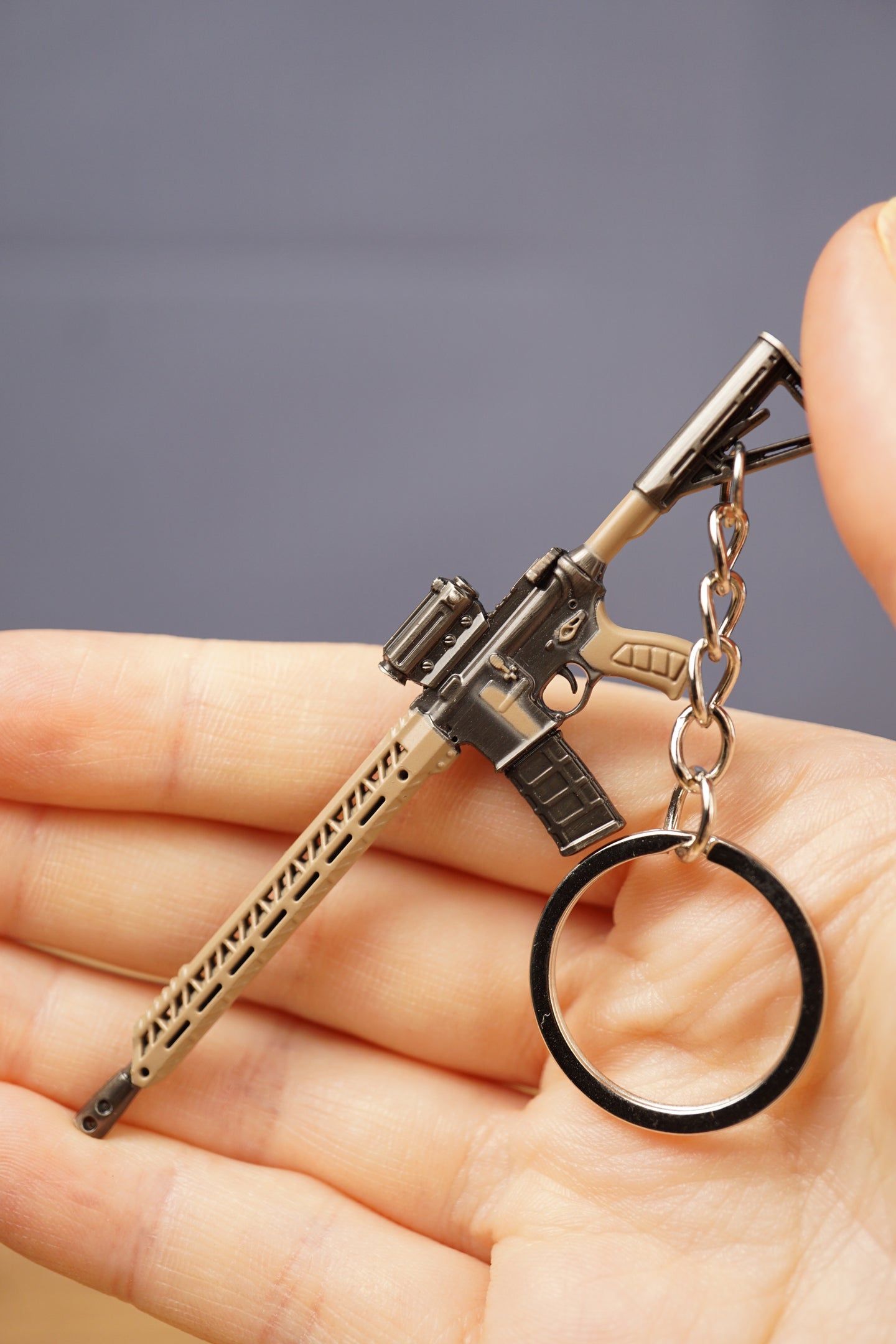Tan rifle keychain with metal ring displayed in hand, ideal as a battle royale or tactical shooter gamer gift.