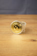 Stack of gold Bitcoin replica coins in clear plastic capsules, with one coin standing upright on a wooden table.